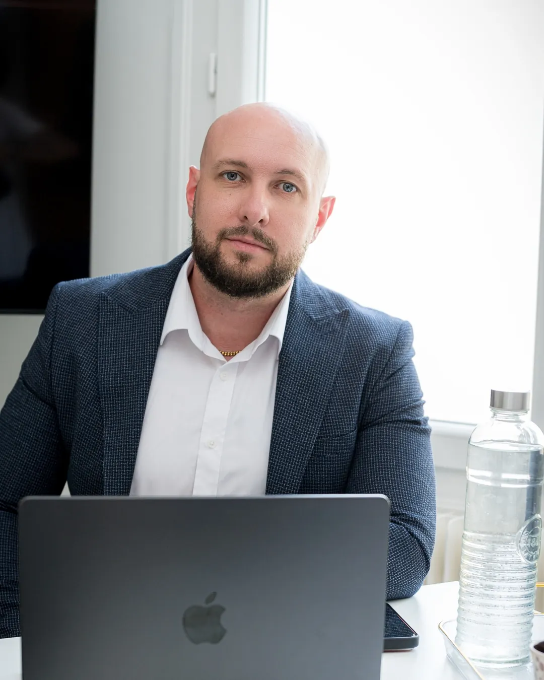 Portrait de Yann Nachtrieb à son bureau, en veste bleu nuit, regard droit